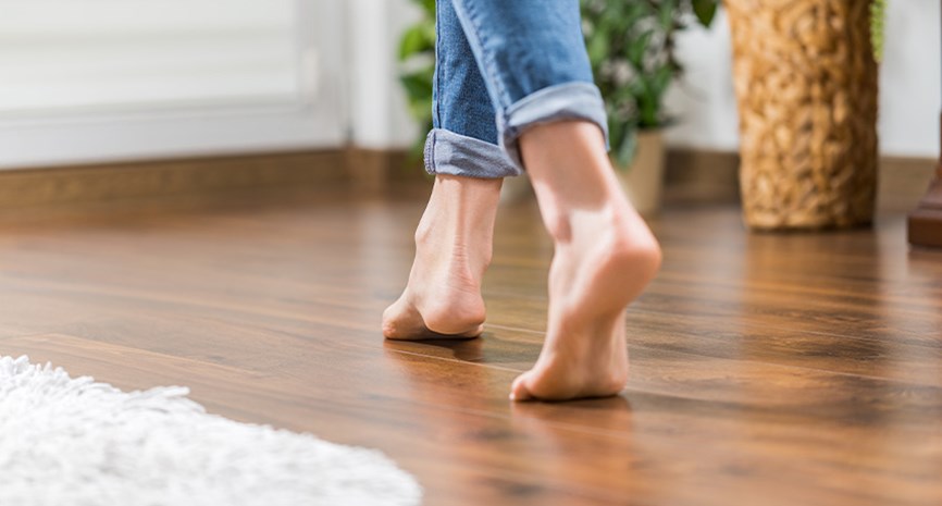 Barbeinte føtter på et gulv med vannbåren gulvvarme
