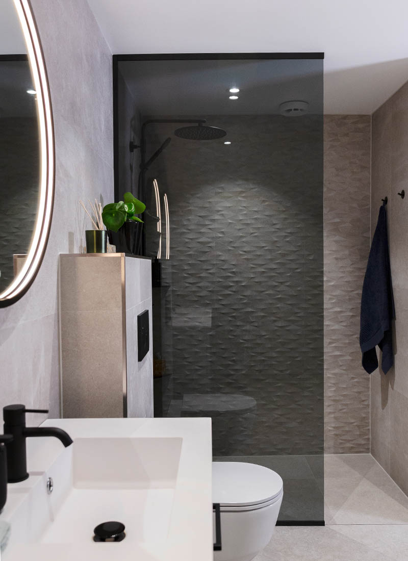 Drømmebad med fliser med 3D-effekt og sort dusjvegg